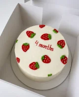 Білий торт з полуничками і написом «4 months» у коробці