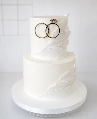 Zweistöckige weiße Hochzeitstorte mit Eheringen
